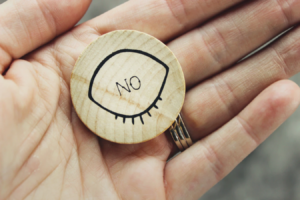 hand holding a wooden token that reads "no"