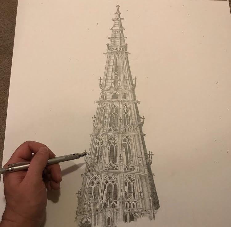 a left hand holding a pencil and drawing a detailed gothic church tower